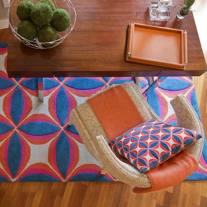 公司房间，有蓝色的地毯和枕头, orange and white, cream chair with orange throw, wooden desk and décor