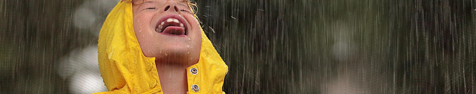 健康保险公司的视频中，一个穿着黄色连帽雨衣在雨中玩耍的男孩的全景图像