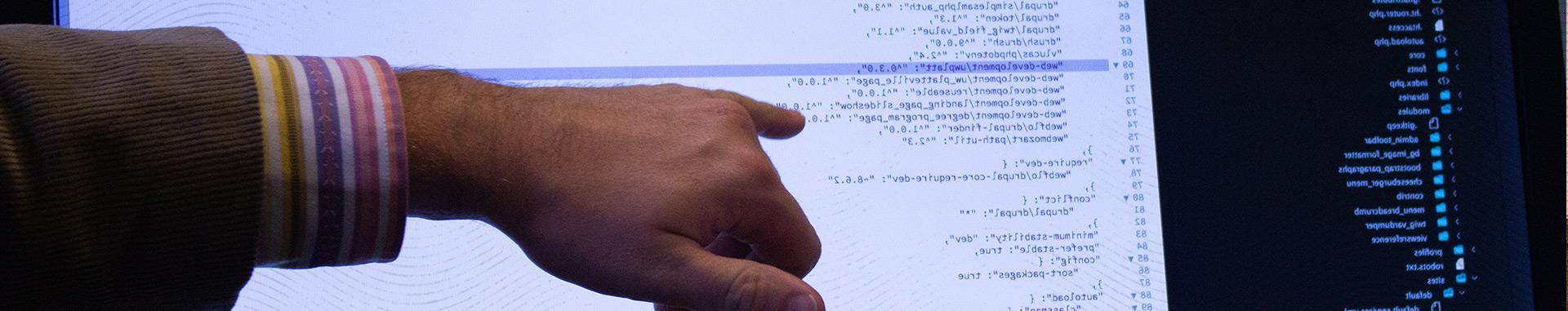 一名Vendi男性员工的手和前臂在电脑屏幕上指出特定的web开发代码